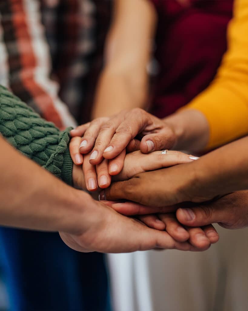 Foto di mani al centro di un gruppo di persone